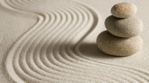 Drei übereinandergestapelte Meditationssteine im Sand Drei übereinandergestapelte Meditationssteine im Sand